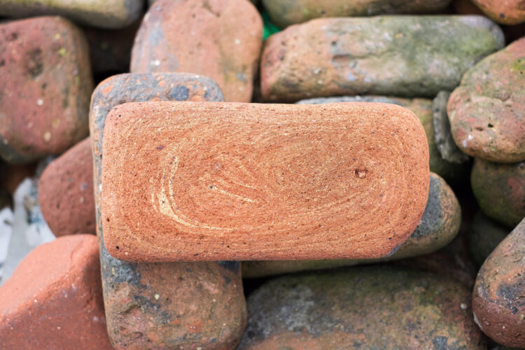 A pile of bricks, all with rounded corners and worn surfaces from being on the beach for decades