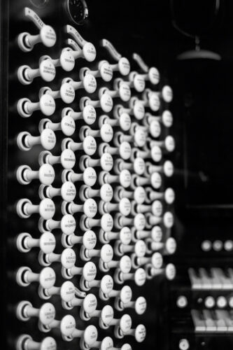 several rows of organ stops - small, white levers that are pushed in and pulled out to change the way the organ sounds. there are around 70 stops visible