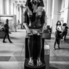 A granite statue of the pharaoh Amenhotep the Third, in the British Museum, with visitors milling around.