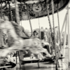 A young girl sitting on a merry-go-round, smiling as she's enjoying the ride