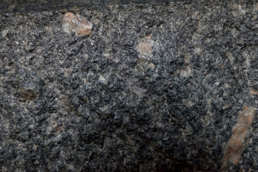 A closeup of the worn surface of a black granite stateu