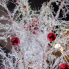 Looking up at a large Christmas-tree-like decoration made of a multitude of white LED lights, metal poles and large, red baubles