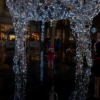 One of the girls standing underneath a large reindeer made of white LED lights wrapped around a metal frame