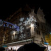 A pattern of large snowflakes being projected onto the side of a large building