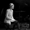 A woman on stage sitting on a stool, singing