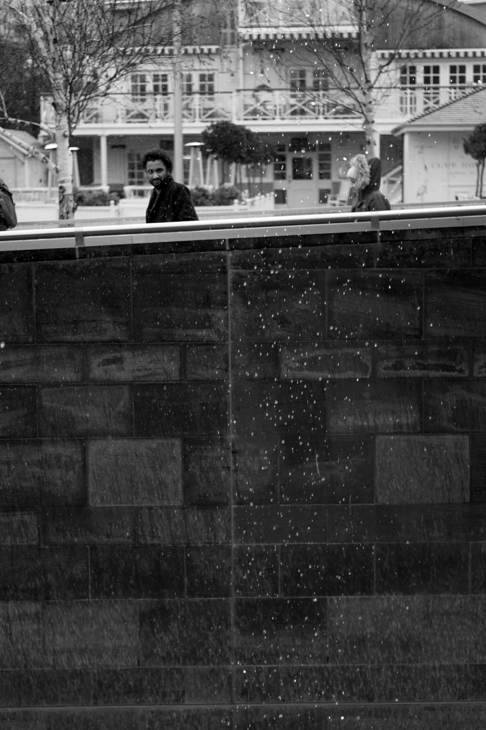 Two people walking past a cascade of water droplets