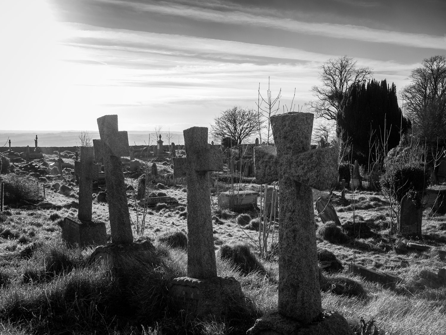 Looking across Lansdown cemetery. In the foreground are three graves with near-identical, plain stone crosses