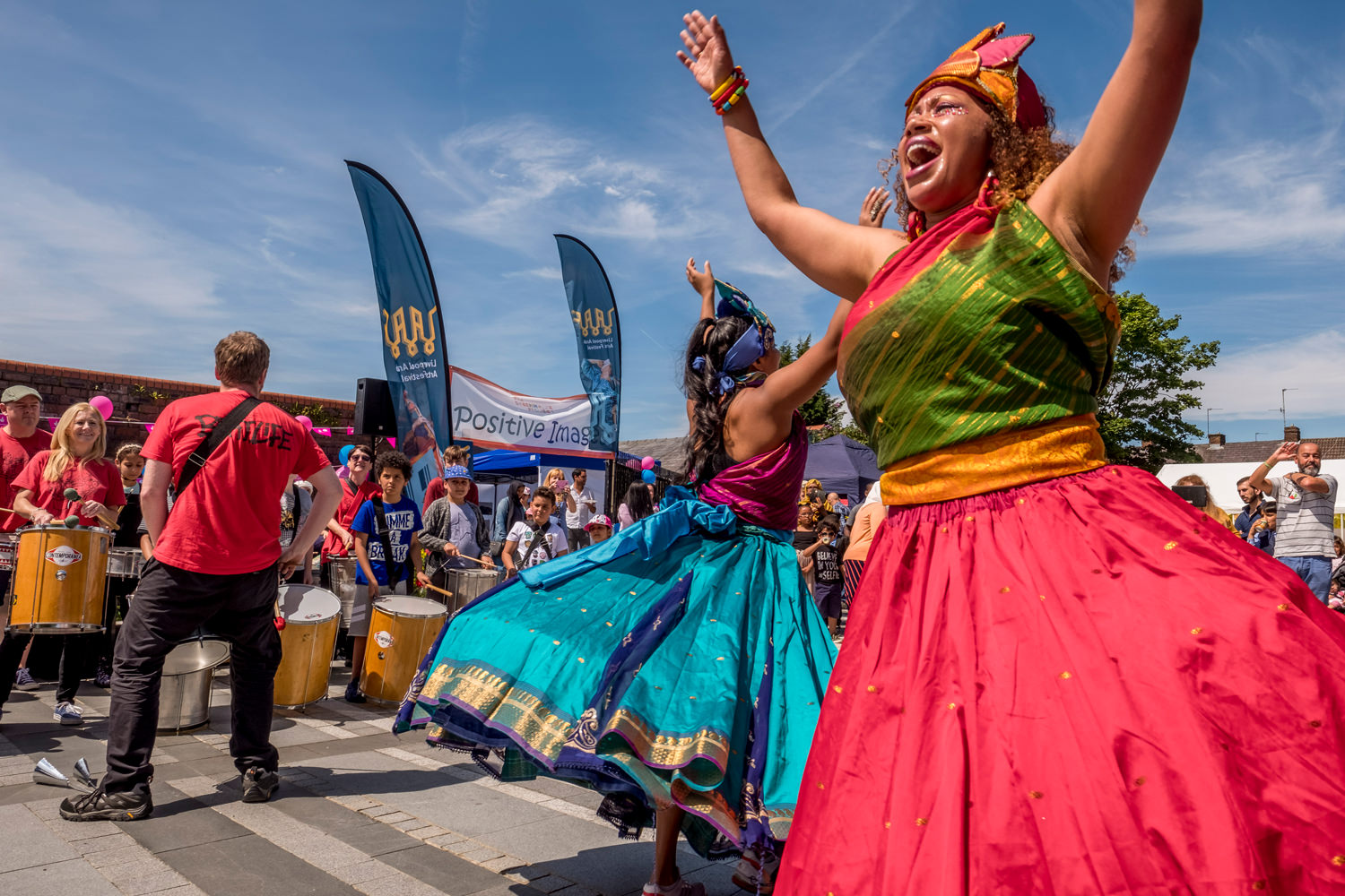 Two dancers in front of a troupe of drummers