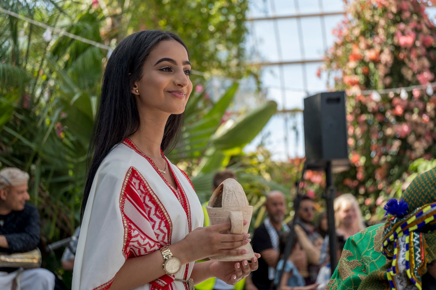 A teenage girl in traditional Arab dress holding a cone-shaped piece of ceramic ware.