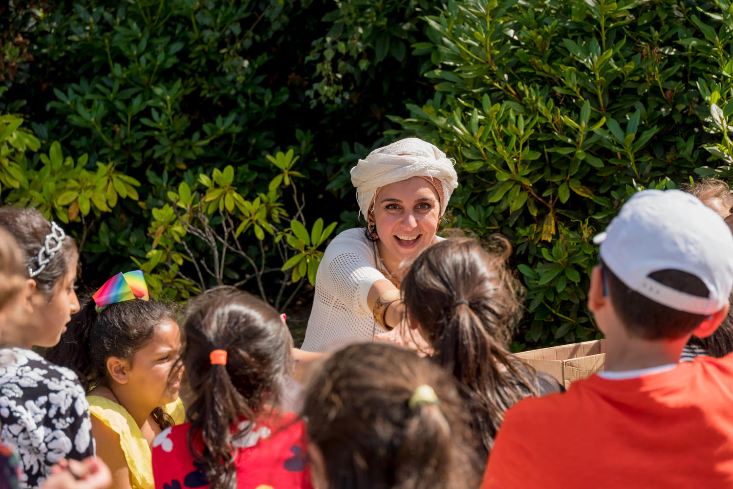 Alia is talking to a group of children. She's pointing and smiling.