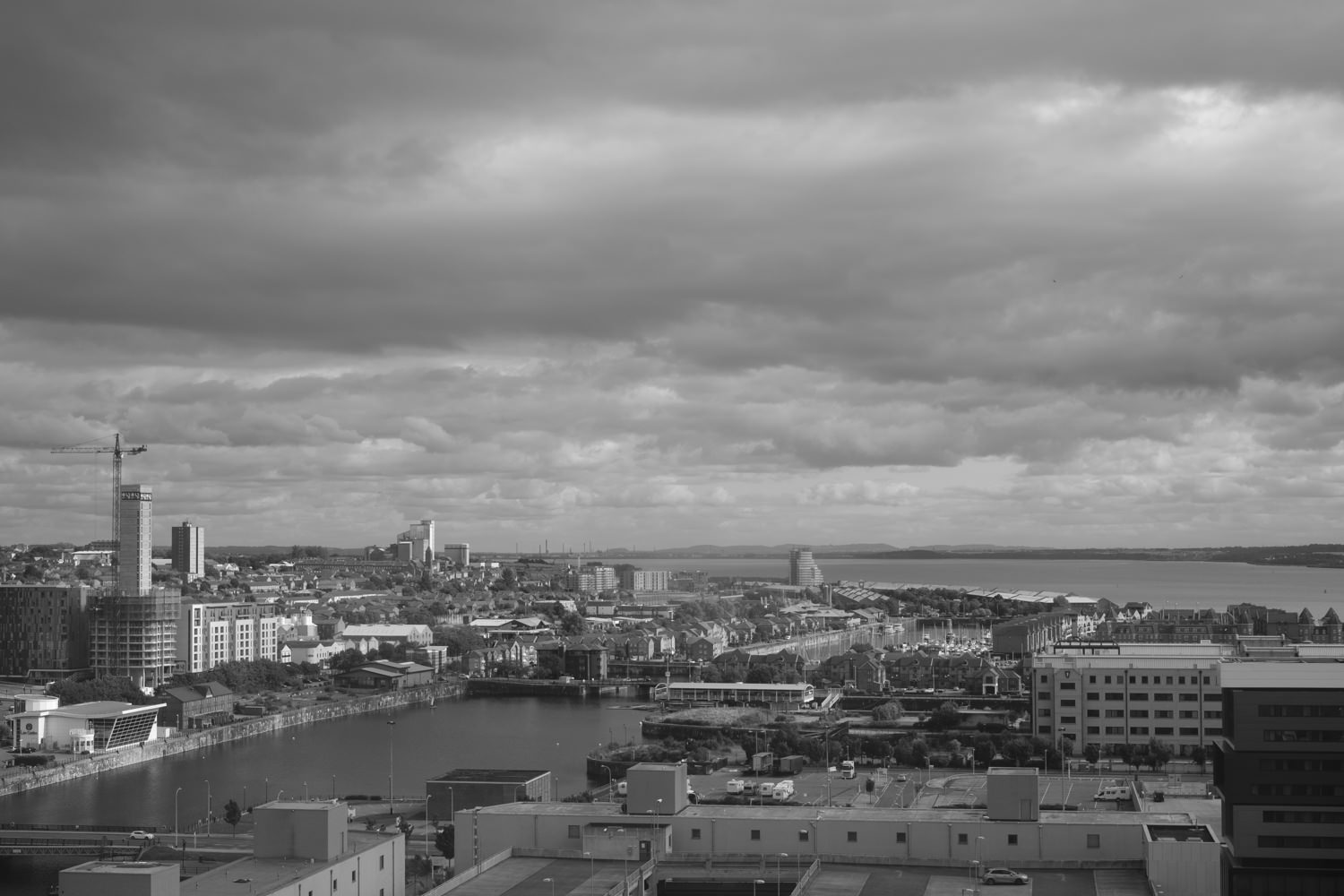 Looking over buildings and part of the river. The sky's full of large clouds.