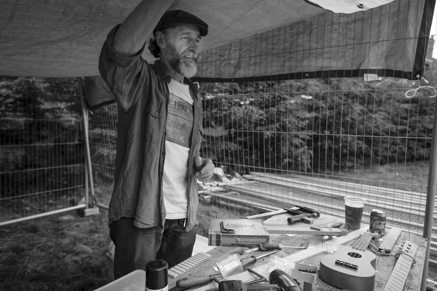 Dennis Sainter in his canvas gazebo, looking out, talking to someone.