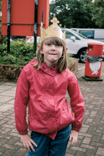 A girl posing with a burger king paper crown