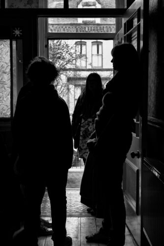 silhouettes of people standing by a front door, talking