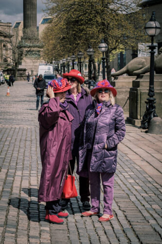 three ladies in purple coats and red hats