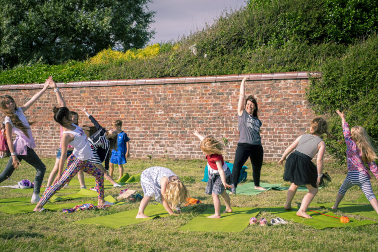 a woman taking a yoga class for children in a park